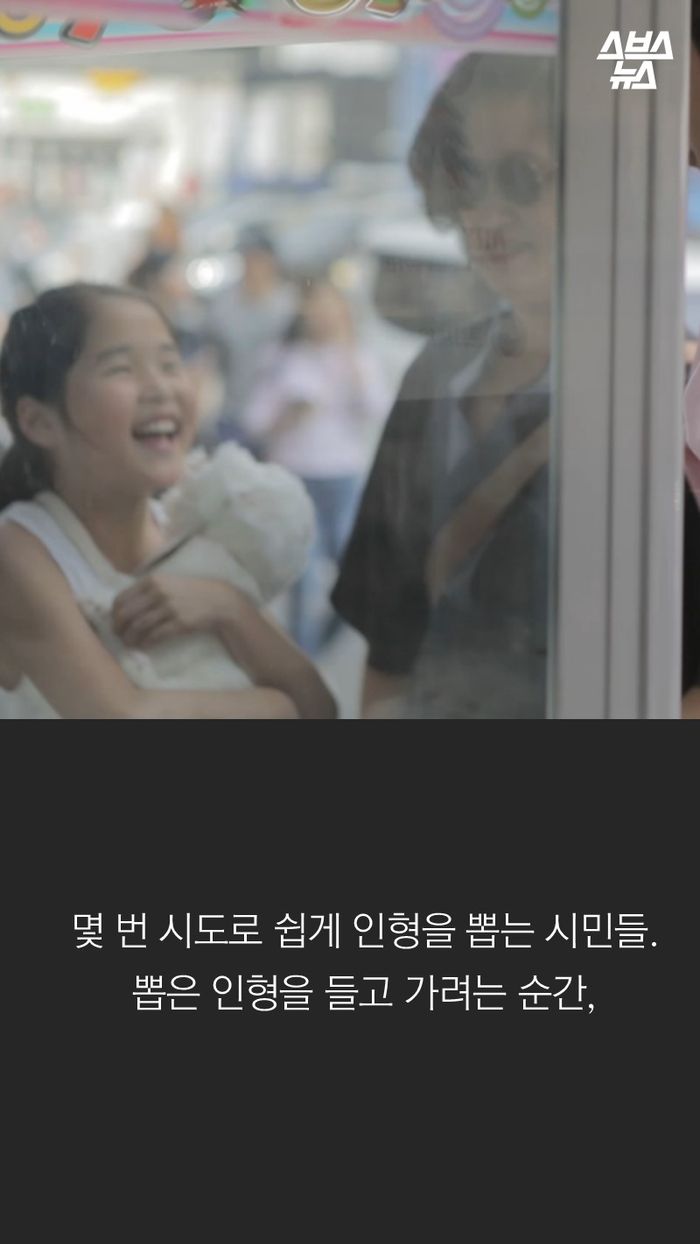 몇 번 시도로 쉽게 인형을 뽑는 시민들.뽑은 인형을 들고 가려는 순간,