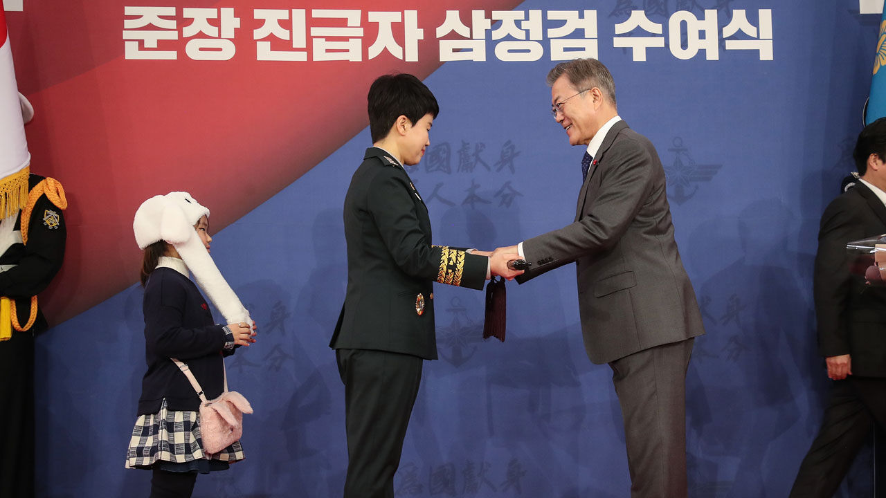 문재인 대통령이 8일 오후 청와대 춘추관에서 열린 지상작전사령부 창설 부대기 및 준장 진급자 삼정검 수여식에서 준장 진급예정자인 노경희 3사단 부사단장에게 삼정검을 수여하고 있다. 엄마를 따라온 딸 김시현 양이 토끼 모자를 쓰고 바라보고 있다.