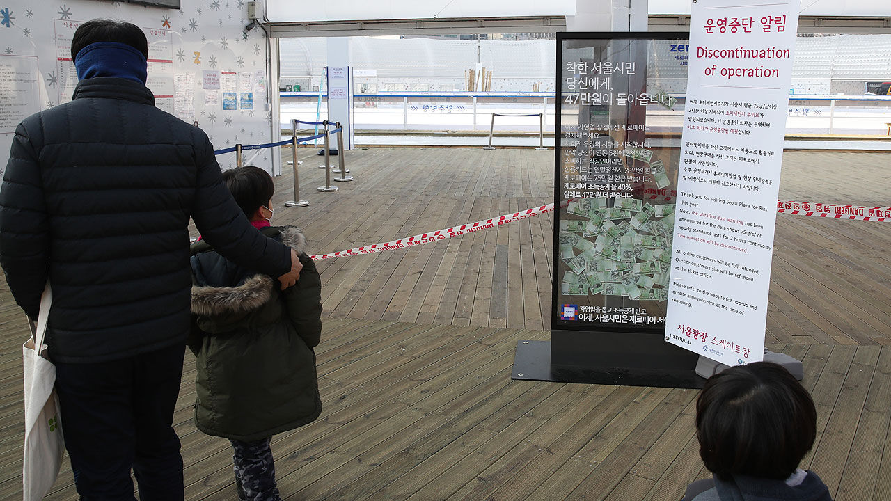 미세먼지 주의보 발령으로 서울광장 스케이트장 운영이 중단된 13일 한 가족이 운영중단 알림 안내문을 보고 있다.