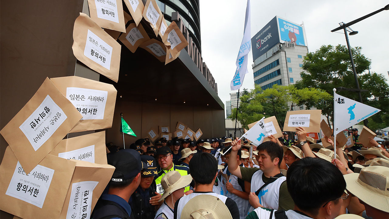 27일 오전 서울 종로구 주한일본대사관 건물 입구에서 서울지역 자주통일선봉대 발대식 참석자들이 강제동원 사죄배상 요구, 경제보복 일본 아베 정권 규탄 등의 내용이 담긴 항의서한을 대사관 측에 전달하려다 경찰에 막히자 건물 외벽에 서한이 담긴 봉투를 부착하고 있다.