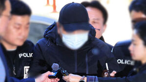 검은 모자와 마스크를 쓴 피의자가 경찰에 둘러싸여 이동하는 모습