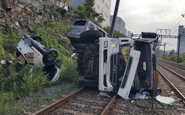 메인이미지  2 :  6일 오전 7시 22분께 부산시 사상구 주례동 보훈병원 맞은편 철길인근에서 정화조 청소를 하던 탱크로리 차량이 주차돼있던 차량 2대를 들이받으면서 경부선 상행성 철길로 함께 떨어졌다. 사진은 떨어진 탱크로리 모습. (부산=연합뉴스)