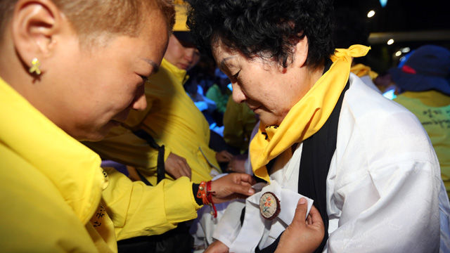 메인이미지  3 : 35주년 5&middot;18광주민주화운동 기념식을 하루 앞둔 17일 오후 광주 동구 금남로 거리에서 열린 전야제에서 세월호 단원고 희생자 가족이 5&middot;18 민주화운동 유족을 만나 추모품을 달아주고 있다. (광주=연합뉴스)