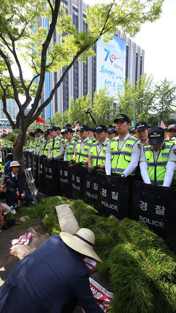 메인이미지  8 : 21일 오후 밥쌀용 쌀 수입 규탄집회를 하기 위해 서울 세종로 정부서울청사 앞으로 이동하던 전국농민회총연맹 회원들이 경찰병력 앞에 모를 던지고 있다. (서울=연합뉴스)