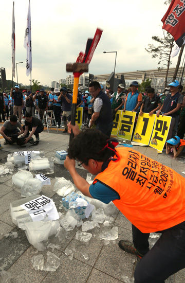 메인이미지  6 : 민주노총 조합원들이 18일 오후 제5차 최저임금위원회 전원회의가 열리고 있는 정부세종청사 고용노동부 앞에서 내년 최저임금을 시급 1만 원, 월급 209만 원으로 올릴 것을 촉구하며 얼음을 깨는 퍼포먼스를 펼치고 있다. (세종=연합)