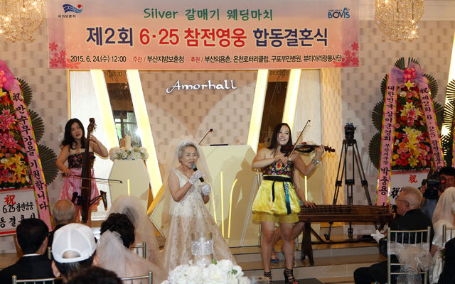 메인이미지  3 : 24일 낮 12시 부산시 부산진구 범천동의 한 웨딩홀에서 6&middot;25 참전용사 부부 9쌍의 합동결혼식이 열린 가운데 한 신부가 트로트 곡인 '내 나이가 어때서'를 부르고 있다. (부산=연합뉴스)