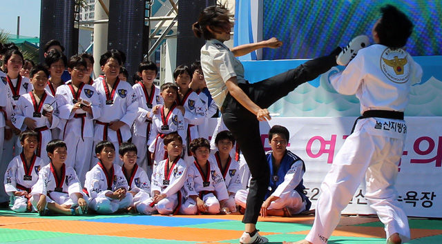 메인이미지  4 :  25일 오후 울산시 동구 일산해수욕장에서 한 여경의 발차기 시범을 어린이들이 지켜보고 있다. 이날 울산 여경 10명이 지역 태권도시범단과 함께 호신술, 체포술 등을 선보였다.
