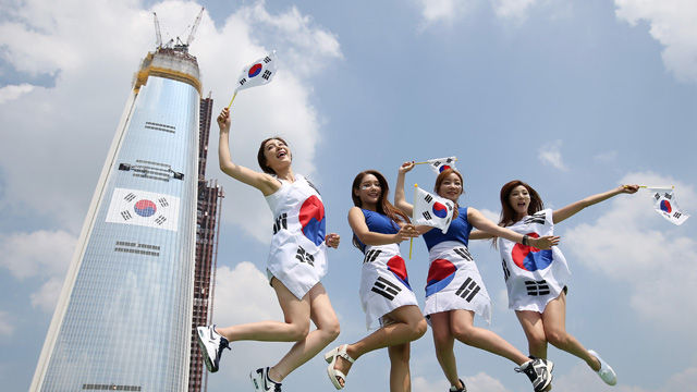 메인이미지  2 : 6일 오후 서울 잠실 롯데호텔 옥상에서 홍보도우미들이 롯데월드 타워에 설치된 태극기를 배경으로 포즈를 취하고 있다. 롯데물산 측은 이날 "광복 70주년을 기념해 롯데월드타워에 가로 36m의 태극기를 설치했다"며 "높이는 약 304m로 국내 최고 높이에 부착된 태극기다"라고 설명했다. (서울=연합뉴스)