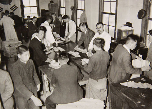메인이미지  9 : 1948년 5월 11일 전날 있었던 선거의 투표용지를 세는 사람들. 개표는 투표 종료 2시간 뒤에 개시되었고 마지막 투표구의 결과가 공개되는 다음날까지 계속될 것으로 예상되었다. (국사편찬위원회 제공)