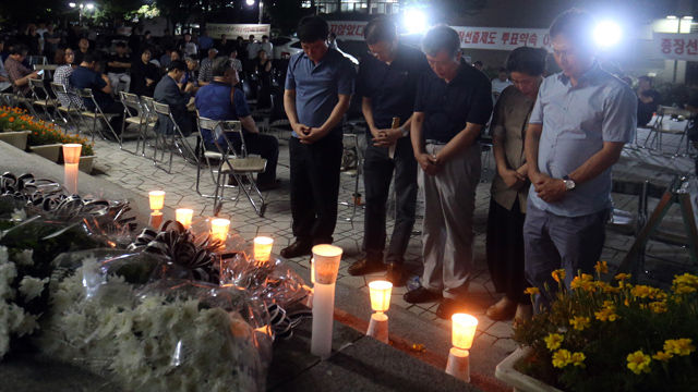 메인이미지  2 : 부산대학교의 한 교수가 17일 총장 직선제 폐지에 반발해 대학 본관 건물에서 투신해 숨진 뒤 동료 교수들이 헌화한 뒤 고인의 명복을 빌고 있다. (부산=연합)