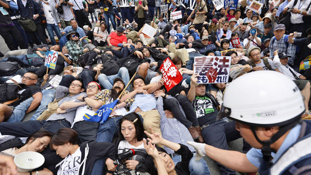 메인이미지  1 : 아베 신조(安倍晋三) 정권의 안보법안 강행처리가 임박한 가운데 16일 오후 일본 가나가와(神奈川)현 요코하마시에서 안보법안에 관한 지방공청회가 끝나고 나서 회의장 주변에 모인 시위대가 스크럼을 짜고 도로에 누워 항의하고 있다. (요코하마 교도=연합)