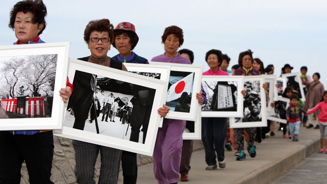 메인이미지  3 : 4일 오후 제주 이호테우해변 인근 매립지에서 다큐멘터리 사진작가 권철씨가 '야스쿠니-군국주의의 망령' 사진전에 전시했던 야스쿠니 사진 40점을 불태우는 퍼포먼스를 선보였다. 퍼포먼스에 앞서 권 작가와 사진전 참가자 등이 사진을 들고 매립지를 행진하고 있다. (제주=연합)