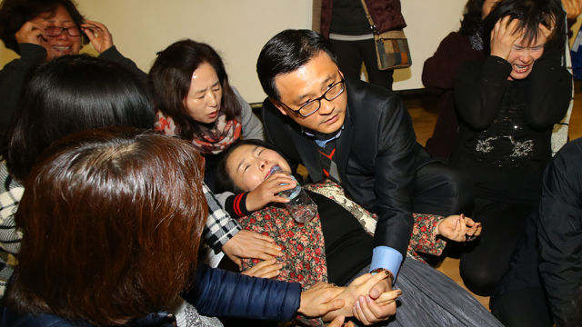 메인이미지  2 : 설명회가 무산으로 오연하던 장애인 가족 여성이 실신하자 주위 사람들이 환자를 돕고 있다.