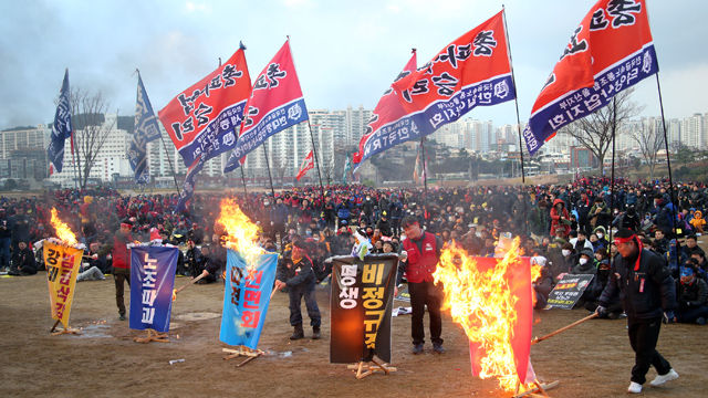 메인이미지  8 : 16일 민주노총 울산 노동자 총파업 결의대회가 열린 울산 태화강 둔치에서 노동자들이 '노조파괴', '평생 비정규직' 등의 구호가 적힌 화형대에 불을 붙이고 있다. 