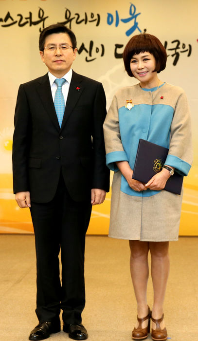 메인이미지  3 : 황교안 국무총리가 24일 서울 세종로 정부서울청사에서 열린 국민추천포상 수여식에서 가수 현숙 씨에게 대통령표창을 수여하고 있다. 현숙씨는 37년간 소외계층에게 무료 위문공연을 펴치고 12대의 목욕차량을 기부한 공로로 표창을 받았다.