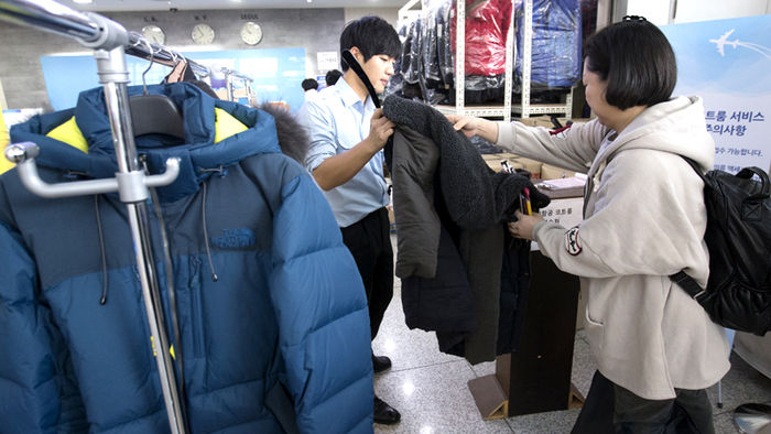 메인이미지  2 : 2015년 마지막 날인 31일 오전 인천국제공항 출국장에서 대한항공 코트룸 서비스 관계자가 손님에게 외투를 받고 있다.
