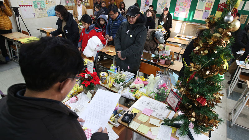 10일 오후 경기도 안산시 단원고등학교에서 열린 '겨울방학식-기억과 약속의 길'에 참석한 시민들이 희생 학생들을 대신해 명예 3학년 교실 자리에 앉아 출석을 부르고 있다.
