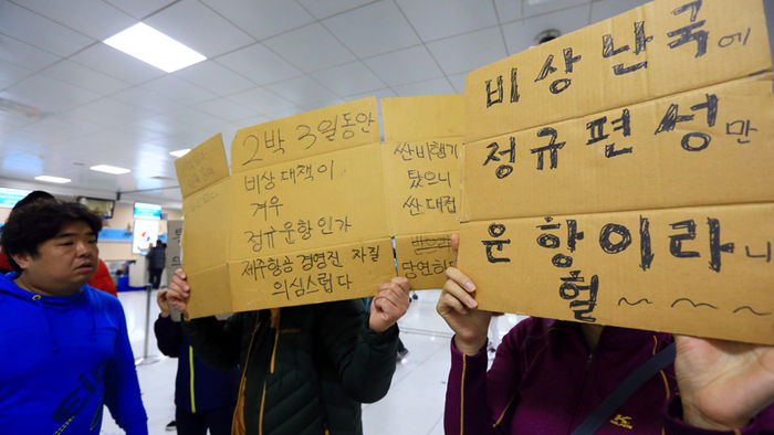 메인이미지  1 : 제주공항의 항공기 운항이 재개된 25일 오후 제주항공 이용객들이 임시편 추가 투입을 요구하는 내용의 글을 적어 항공사에 항의하고 있다.