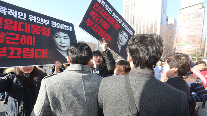 메인이미지  2 : 김무성 대표 등 새누리당 인사가 5일 오후 부산역에서 고향을 찾는 시민에게 인사하는 가운데 민주부산행동 회원이 박근혜 대통령의 한일 위안부 합의를 비판하는 피켓 시위를 벌이고 있다.