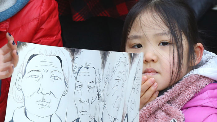 메인이미지  7 : 24일 오후 서울 종로구 옛 일본대사관 앞에서 열린 제1219차 일본군 '위안부' 문제해결을 위한 정기 수요 시위에서 한 소녀가 할머니들의 초상화가 그려진 피켓을 들고 있다.