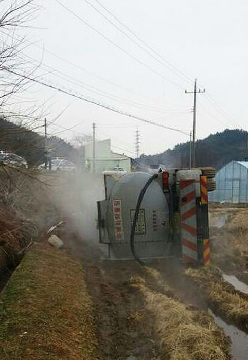메인이미지  3 : 13일 오전 충남 서천군 서면 원두리 앞길에서 염산을 싣고 달리던 탱크로리가 길옆 논으로 전복된 모습. 염산이 새어나오고 있다.