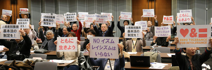 메인이미지  1 : 17일 오후 일본 도쿄도(東京都) 지요다(千代田)구 소재 참의원 의원회관에서 열린 집회에서 참석자들이 인종차별금지법 제정을 요구하는 문구를 비롯해 일본 내 차별을 없애자는 뜻을 담은 종이를 들어 보이고 있다. 