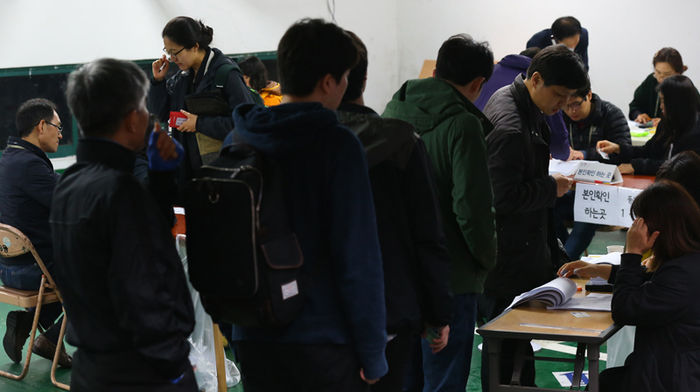메인이미지  3 : 제20대 국회의원선거 투표일인 13일 오전 서울 관악구 대학 제1투표소에서 유권자들이 투표를 위해 선거인명부를 확인을 하고 있다. (서울=연합뉴스)