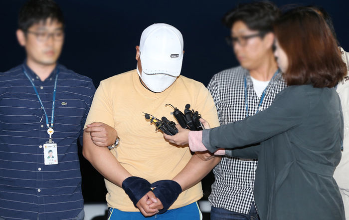 메인이미지  3 : 제주에서 중국인 여성을 살해한 혐의로 긴급체포된 중국인 S(33)씨가 모자와 마스크를 착용하고 고개를 숙인 채 울먹이며 기자들의 질문에 답하고 있다.