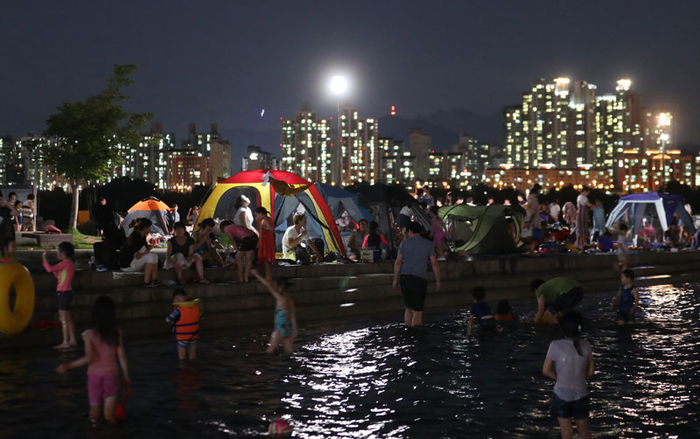 메인이미지  3 : 서울의 낮 최고기온이 35.7도까지 올라 올 들어 최고기온을 경신한 4일 저녁 서울 여의도 한강공원 물빛광장에서 시민들이 더위를 식히고 있다.