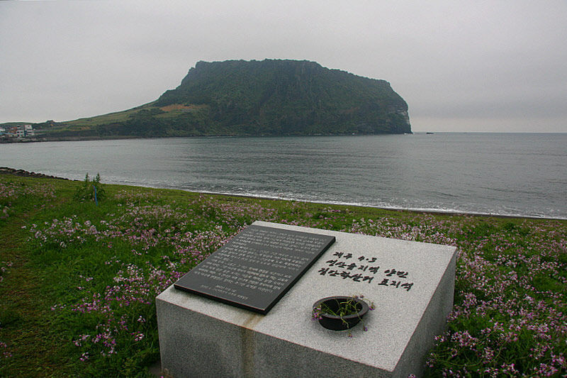 터진목 해안가에 세워진 제주 4.3 성산읍 희생자 집단 학살터 표지석과 성산 일출봉
