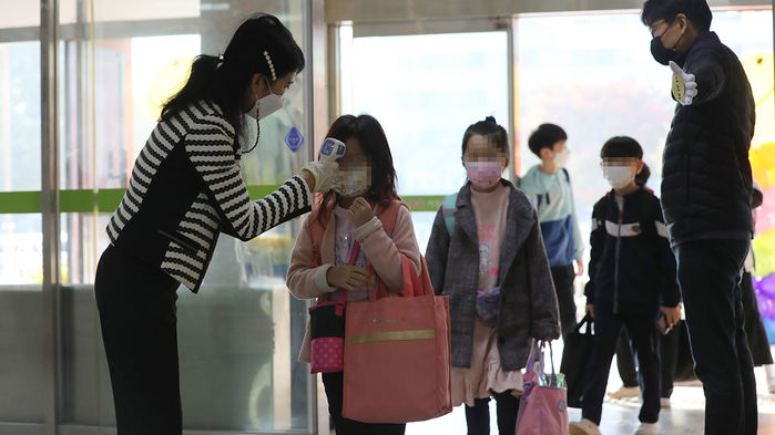 메인이미지  4 : 전면 등교가 시작된 19일 오전 청주시 흥덕구 경산초등학교 학생들이 등교하며 발열 여부를 확인하고 있다.