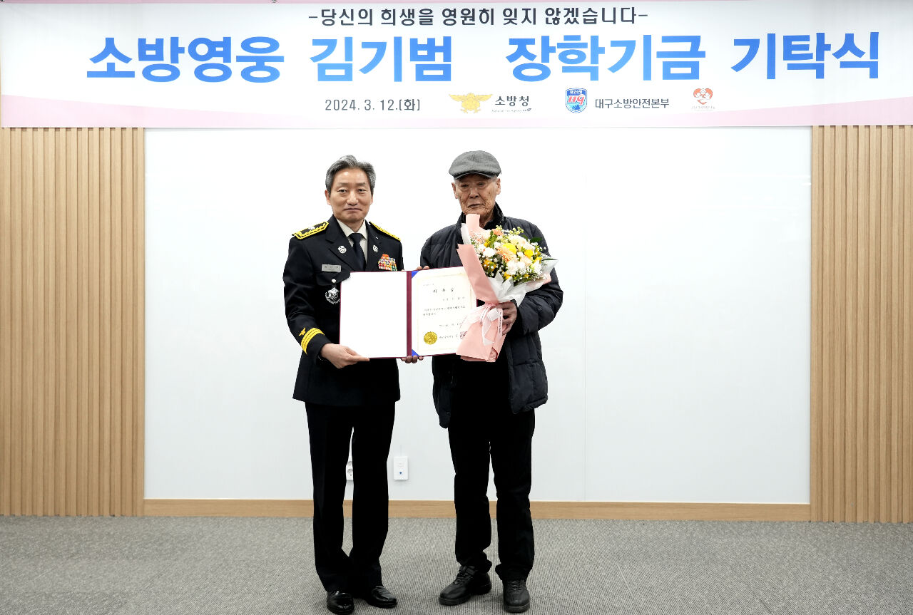 소방영웅？김기범？장학기금 기탁식에서 김경수 씨(오른쪽)와 정남구 대구소방본부장이 기념 촬영을 하고 있다.？