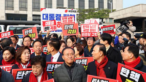 지난 21일 서울 종로구 헌법재판소 앞에서 윤석열 대통령 탄핵 각하 촉구 기자회견을 준비하던 국민의힘 의원들(앞쪽)이 윤 대통령 즉각 파면 촉구 기자회견을 하는 더불어민주당 의원들(뒤쪽)을 바라보고 있다.