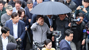 더불어민주당 이재명 대선 후보가 '골목골목 경청투어' 사흘째인 3일 '동해안벨트' 첫 방문지인 강원도 속초시 중앙재래시장에서 비가 그쳤음에도 우산을 쓴 채로 두터운 경호막에 둘러싸여 도민들을 향해 인사하고 있다.