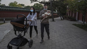 중국 베이징의 한 공원에서 한 부부가 갓 태어난 아기를 안고 걷고 있다.(사진=게티이미지)