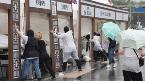서울에 호우주의보가 내려진 20일 서울 청계광장에서 열린 한 행사장에서 관계자들이 강한 비바람이 불자 시설물을 잡고 있다.(사진=연합뉴스)