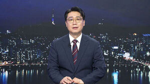 안경을 쓴 남성 앵커가 서울 야경 배경의 뉴스 스튜디오에서 정면을 응시하고 있다.