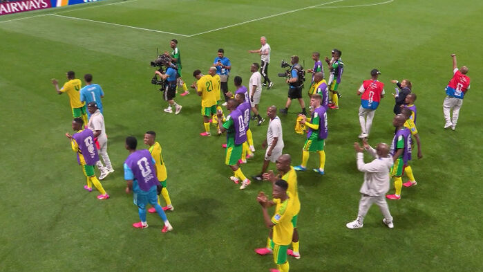 축구 경기 후 노란색 유니폼을 입은 선수들이 관중에게 인사하며 경기장을 걸어가는 모습.