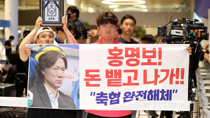2026 북중미 월드컵 32강 진출에 실패해 한국 축구 국가대표팀에서 사퇴한 홍명보 전 감독이 입국하는 30일 인천국제공항 제2여객터미널을 찾은 팬들이 항의 현수막을 들어올리고 있다.