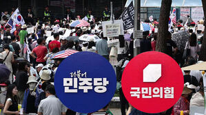 더불어민주당과 국민의힘 로고가 크게 배치된 화면 뒤로 태극기와 성조기를 든 집회 인파가 모여 있음.