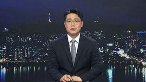 안경을 쓴 남성 앵커가 서울 야경을 배경으로 뉴스를 진행하고 있다.