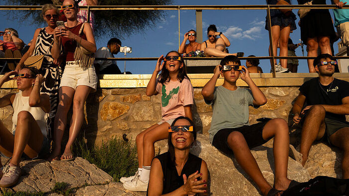 Vacationers wearing solar eclipse glasses and watching a total solar eclipse in L'Escala, Spain, on August 12, 2026 (Photo: Getty Images)