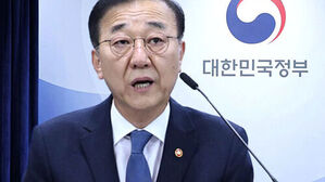 대한민국정부 로고 배경 앞에서 발언하는 안경을 쓴 남성