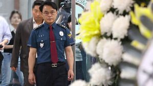 경찰 정복을 입은 남성이 국화꽃 옆을 지나고 있다.