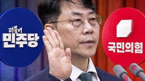 민주당과 국민의힘 로고를 배경으로 손을 들고 발언하는 안귀령 대변인