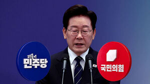 안경을 쓴 남성이 마이크 앞에 서 있고 양옆에 더불어민주당과 국민의힘 로고가 보임