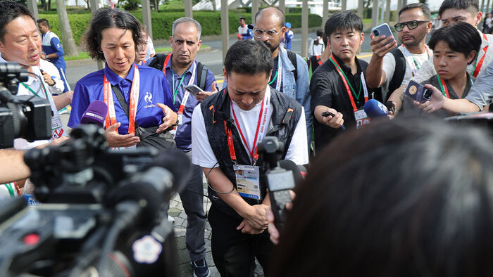 An organizing committee official explains the situation and apologizes to the press after the welcoming ceremony held at the square near the athletes' accommodation in the Port of Nagoya on September 18, one day before the opening of the 2026 Aichi-Nagoya Asian Games, was delayed by about 1 hour and 30 minutes due to the organizing committee's poor operations.