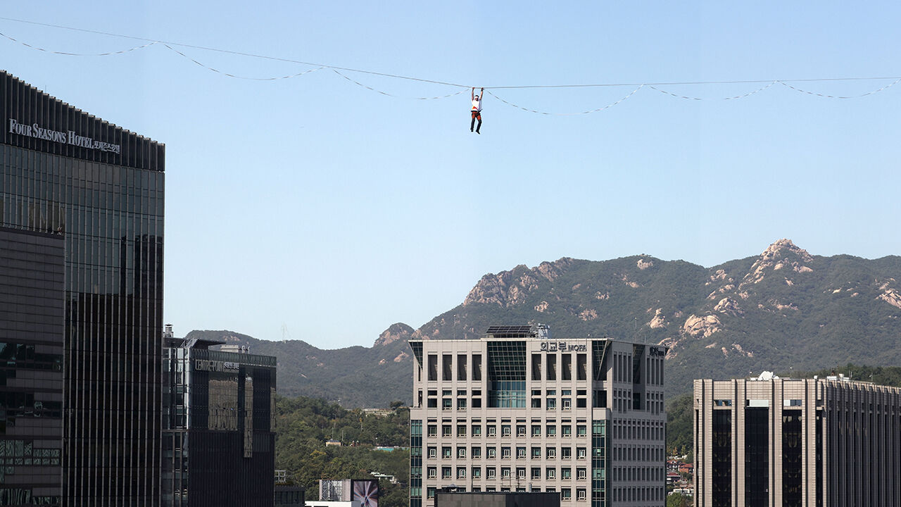 Slackline athlete Jaan Roose performs stunts in the air above Sejong-daero, in front of Cheonggye Plaza in Seoul, on the 1st, walking and showcasing various skills while balancing on a tightrope. (Photo: Yonhap News)