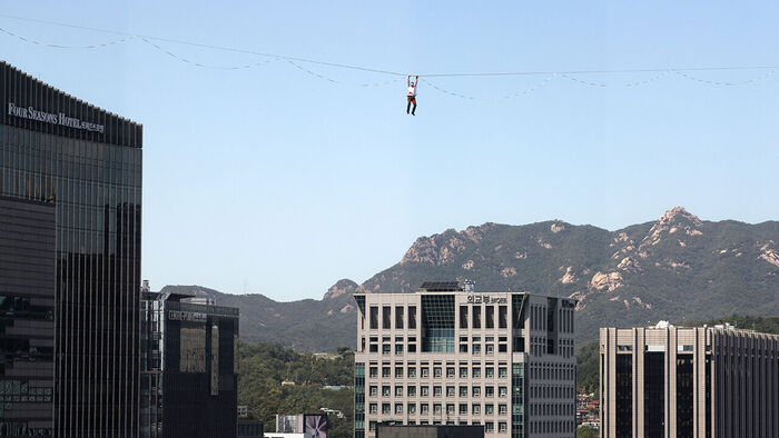 Slackline athlete Jaan Roose performs stunts in the air above Sejong-daero, in front of Cheonggye Plaza in Seoul, on the 1st, walking and showcasing various skills while balancing on a tightrope. (Photo: Yonhap News)