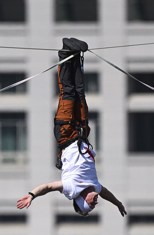 Slackline athlete Jaan Roose performs stunts in the air above Sejong-daero, in front of Cheonggye Plaza in Seoul, on the 1st, walking and showcasing various skills while balancing on a tightrope. (Photo: Yonhap News)